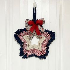 a red, white and blue wreath hanging on the front door with a bow around it