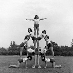 a group of young women standing on top of each other in a circle with their arms spread out