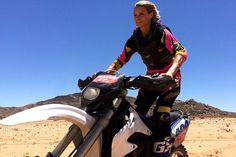 a woman riding on the back of a white dirt bike in the middle of nowhere