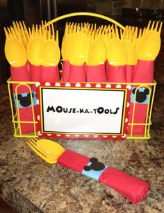a table topped with yellow and red plastic utensils next to a sign that says moue - ka - lou