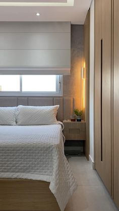 a white bed sitting under a window in a bedroom