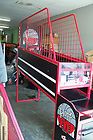 a man standing in front of a red metal cage on top of a baseball field