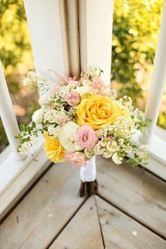 a bouquet of flowers sitting on top of a wooden floor next to an open window