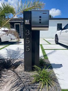a black mailbox sitting in the middle of a driveway next to a white car