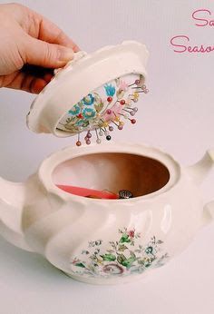 a person is pouring tea into a white teapot with floral designs on the lid