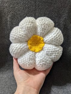 a crocheted white flower with yellow center being held by someone's hand