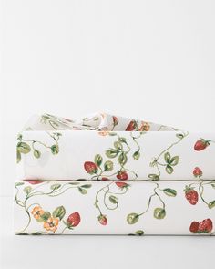 two sheets with strawberries on them are folded up in front of each other,