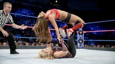 two women wrestling in an arena with referee