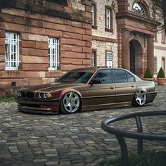 a brown car parked in front of a brick building on a cobblestone street