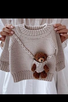 a person holding up a sweater with a teddy bear on it