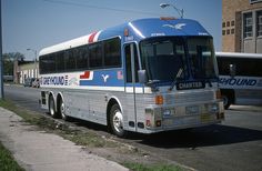 a blue and white bus parked on the side of the road next to another bus