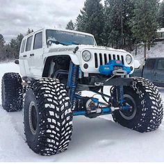 a white jeep is parked in the snow with four wheels on it's tires