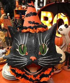 a black cat mask sitting on top of a table next to other halloween decorations and pumpkins