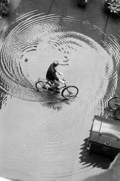 a man rides his bike through a flooded street