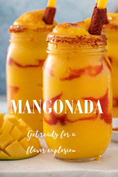 two mason jars filled with mangoade sitting on top of a table