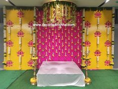 a bed sitting in front of a wall covered in yellow and pink fabric with candles