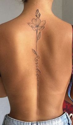 the back of a woman's body with a flower tattoo on her lower back