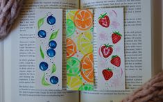 an open book with fruit on it and some yarn next to the bookmarks