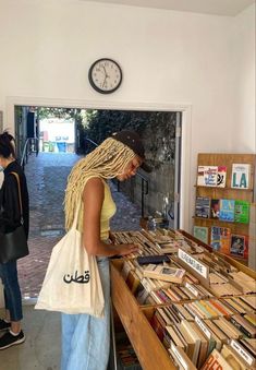 a woman standing in front of a counter filled with books