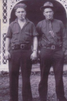 two men standing next to each other in front of a building