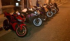 a row of motorcycles parked next to each other on the side of a street at night