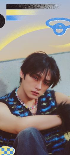 a young man sitting on top of a blue and yellow wall next to a skateboard