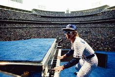 a man with sunglasses and a baseball cap playing the piano in front of an audience