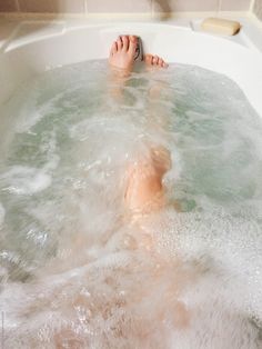 a person laying in a bathtub with their feet up