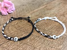 two personalized bracelets sitting on top of a wooden table next to a flower