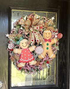 a wreath decorated with gingerbreads and candy canes is hanging on the front door