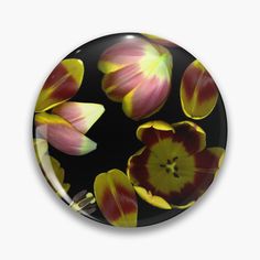 a black and yellow flower pattern on a round glass button or magnet with the image of tulips