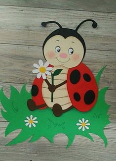 a paper cut out of a ladybug sitting on top of grass with a flower