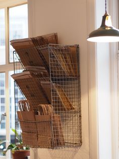 a metal basket hanging from the side of a wall filled with boxes and folders