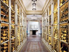 a long hallway with lots of wine bottles on the walls and in between them is a chandelier