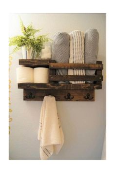 a bathroom shelf with towels and other items hanging on it's sides, along with a potted plant