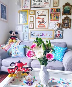 a living room filled with furniture and lots of pictures on the wall above it's coffee table