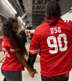 two people in red jerseys are walking down the hallway