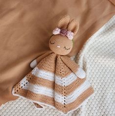 a crocheted stuffed animal laying on top of a bed next to a blanket