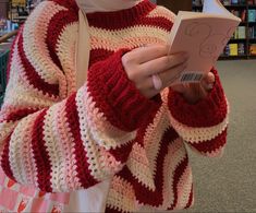 a woman is holding a book in her hands and wearing a red and white striped sweater