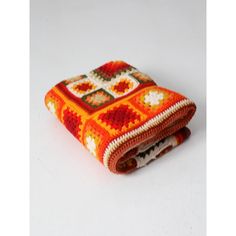 an orange crocheted blanket folded on top of each other in front of a white background