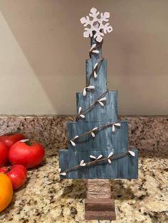 a blue christmas tree with white snowflakes on it sitting next to some tomatoes