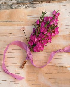 purple flowers are tied to a piece of wood