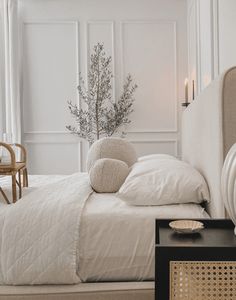 a bed with white sheets and pillows next to a night stand in a room filled with furniture