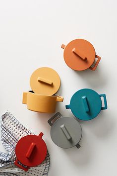 three teapots and two napkins on a white surface with the lids off