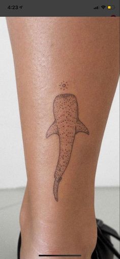 a woman's leg with a tattoo on it that looks like a whale swimming in the ocean