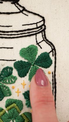 a person is stitching shamrock leaves in a jar