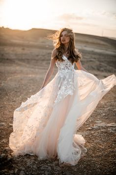 a woman in a long white dress is standing on the ground with her hair blowing in the wind