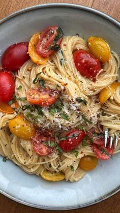 a white bowl filled with pasta, tomatoes and parmesan cheese