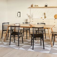 a dining room table and chairs in front of a white wall with geometric pattern on the floor