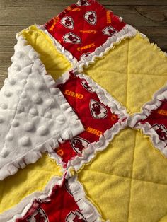 a quilted table topper with red and yellow squares on the bottom, white ruffles around the edges